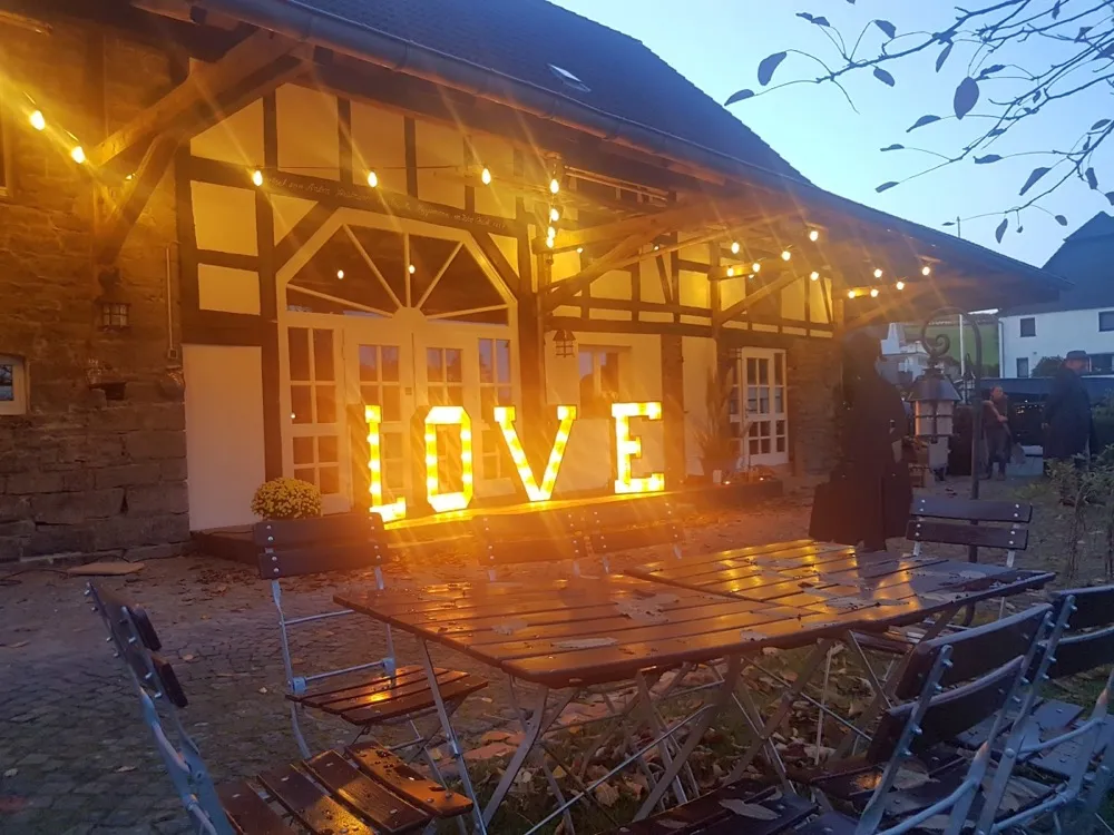 Beleuchtete XXL-Buchstaben LOVE vor einem Fachwerkhaus bei Dämmerung